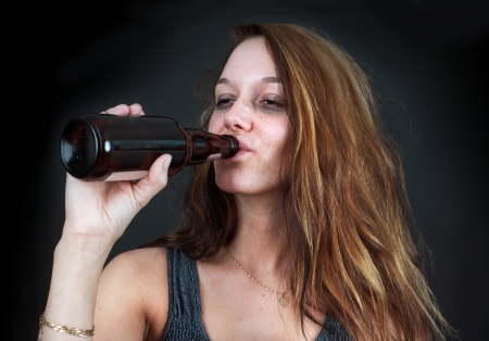 Portrait of drunk young woman drinking beer over blackの写真素材