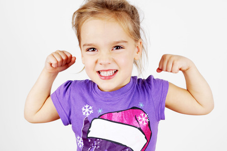 Cute and funny little blond girl showing her muscleの写真素材