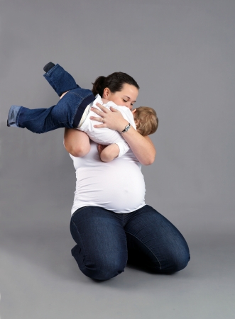 Pregnant mother playing and kissing her little boy or toddler.の写真素材