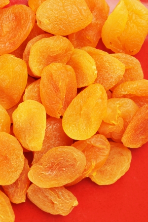 Heap of sweet dried apricot fruits on red plate, colorful food backgroundの写真素材