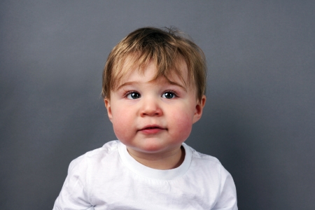 Portrait of cute little blond baby boy or toddler over grey backgroundの写真素材