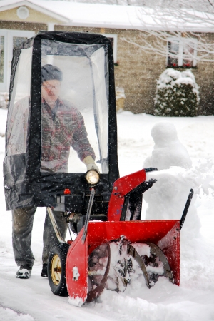 Man using snowblower in his home entryway during a winter blizzardの写真素材