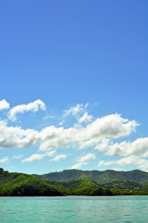 Tropical island, forest and sky, view from the water, verticalの写真素材
