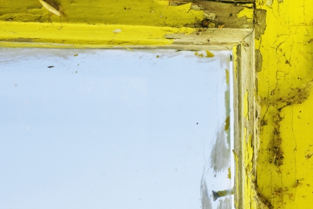Old and dirty yellow painted wooden window frame and glass, with cobwebの写真素材