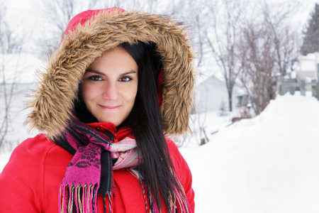 Portrait of beautiful young woman with red winter coat outdoorsの写真素材