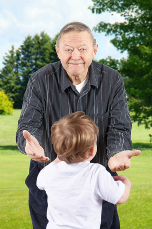 Happy senior man or grand father bending down with open arms to welcome grand kids.の写真素材