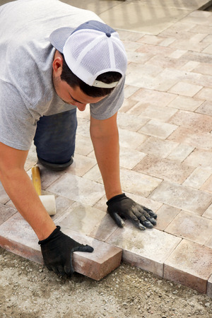Landscaping concept: man, worker or trade putting down paver stones, verticalの写真素材