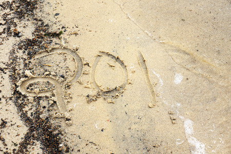 New year concept: year 2014 (or other number) written on the beach being washed away by a waveの写真素材