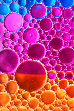 Oil drop and water over red, orange, pink and blue background-fun abstractの写真素材