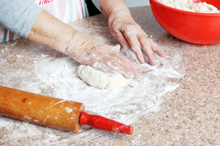 Senior woman hands making dough for a pie in her home kitchenの写真素材