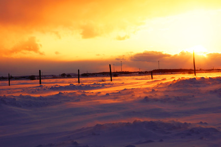 Beautiful sunset over snow on cold and windy winter dayの写真素材