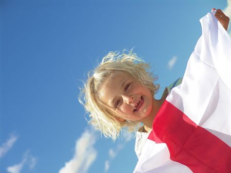 Young girl with blonde hair smiling and holding sheetの写真素材