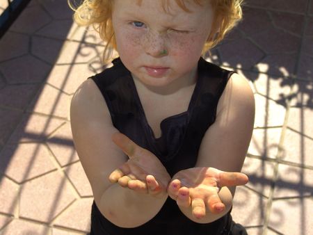 Cute young girl holds out hands dirty with paintsの写真素材