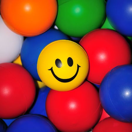 Smiling face amongst brightly colored ballsの写真素材