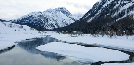 Landscape of a frozen mountain river and snow-capped mountains