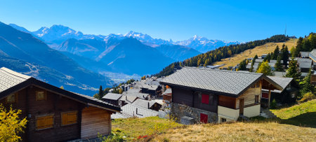 Panoramic view of alpine village with snow capped mountains in background.の写真素材