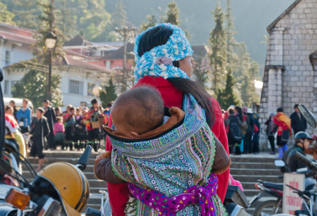 SAPA, VIETNAM - DEC 16: Hmong woman carrying her child in her backpack on December 16, 2012, in Sapa, Vietnam.The majority of citizens in Sapa are Hmong and Dao people for over 70% of the populationのeditorial素材