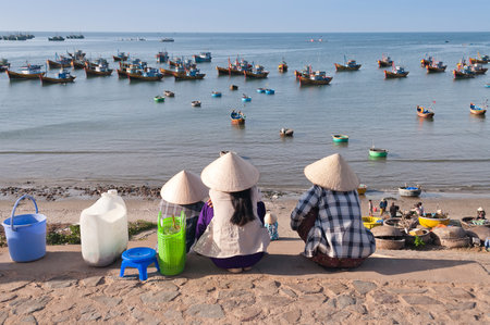 MUI NE, VIETNAM - DEC 21: Three women in conical hats in Fishing village? on Dec 21, 2012, in Mui Ne, Vietnam. Mui Ne is a coastal resort town.  Tourism has transformed Mui Ne into a resort destination since 1995.のeditorial素材