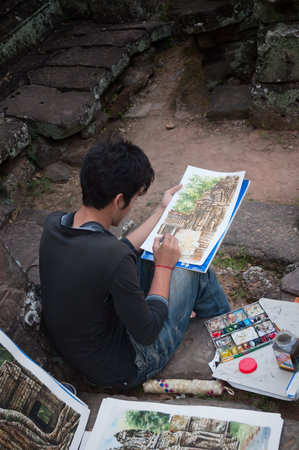 SIEM REAP, CAMBODIA - DEC 26  Cambodian young artist paints a picture for sale to tourists at Banteay Kdei temple on Dec 26, 2012, in Siem Reap, Cambodia  Banteay Kdei is a Buddhist temple in Angkorのeditorial素材