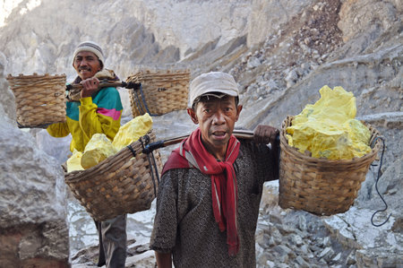 Worker carrying sulfur inside Ijen crater on December 3, 2011   Workers pick up the 60-90 kg basket with the sulfur  The work is low-paid and very onerous  のeditorial素材