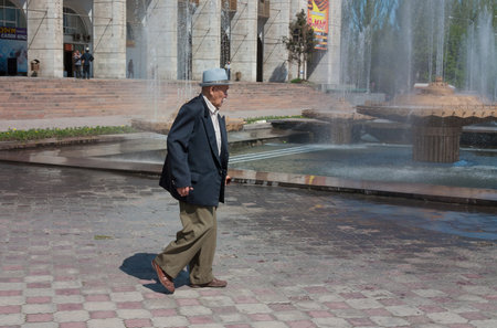 BISHKEK, KYRGYZSTAN - MAY 02, 2014: Elderly asian man walking on Ala-Too Square. Bishkek formerly  Frunze, is the capital and the largest city of the Kyrgyz Republic.  The population - 900,000 peopleのeditorial素材