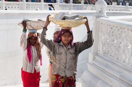 AMRITSAR, INDIA, DEC - 7, 2014: Unidentified women carry basket of stones on their head at Golden Temple (Harmandir Sahib also Darbar Sahib). Golden Temple is the holiest Sikh gurdwara located in the city of Amritsar, Punjab, India.のeditorial素材