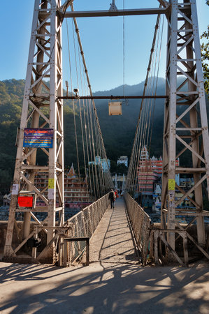 RISHIKESH, INDIA - DEC 11, 2014: Laxman Jhula bridge over Ganges river.  People crossing footbridge. Rishikesh is  World Capital of Yoga,  has numerous yoga centres that also attract touristsのeditorial素材