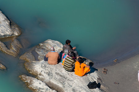 RISHIKESH, INDIA - DEC 11, 2014: Unidentified Indian family sitting on a rock at the River Ganga. Rishikesh is  World Capital of Yoga,  has numerous yoga centres that also attract touristsのeditorial素材