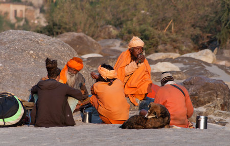 RISHIKESH, INDIA - DEC 11, 2014: Unidentified Indian sadhus siting on the beach near River Ganga. Rishikesh is  World Capital of Yoga,  has numerous yoga centres that also attract touristsのeditorial素材
