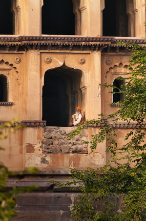ORCHHA, INDIA - DEC 19, 2014: Unidentified Indian Sadhu sitting at window of Chaturbhuj Temple. Orchha is a town in Madhya Pradesh state. The town was established by Maharaja Rudra Pratap Singh in 1501のeditorial素材
