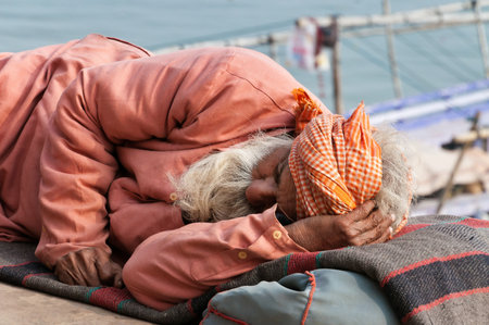 VARANASI, INDIA - DEC 23, 2014: Unidentified Indian man sleeps on the ghat near sacred river Ganges in Varanasi. Uttar Pradesh, Indiaのeditorial素材