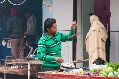 VARANASI, INDIA - DEC 24, 2014: Unidentified Indian seller with weights on the street in Varanasi. Uttar Pradesh, Indiaのeditorial素材