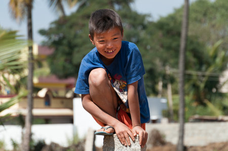 BANGALORE, INDIA - DEC 26, 2014: Unidentified Indian boy on stone pillar on the street in Bangalore.  Karnataka. Indiaのeditorial素材