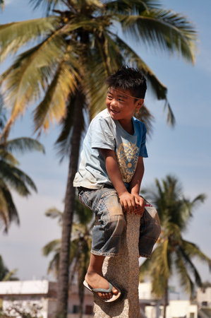 BANGALORE, INDIA - DEC 26, 2014: Unidentified Indian boy on stone pillar on the street in Bangalore.  Karnataka. Indiaのeditorial素材