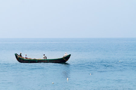 KOVALAM, INDIA - DEC 28, 2014: Traditional wooden fishing boats in the ocean. Kovalam. Kerala. Indiaのeditorial素材