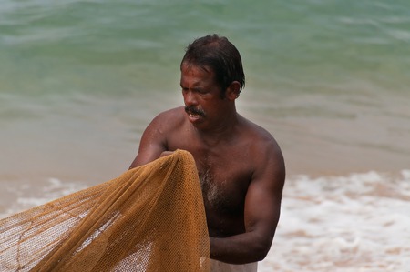 KOVALAM, INDIA - DEC 28, 2014: Unidentified Indian Fisherman with fishing neton Samudra beach in Kovalam. Kerala. Indiaの写真素材