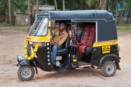 KOVALAM, INDIA - DEC 28, 2014: Indian auto rickshaw with taxi driver man in fishing village....