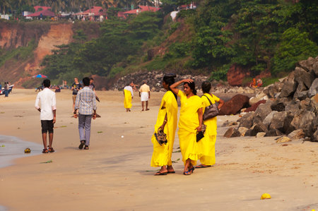 VARKALA, INDIA - DEC 30, 2014: Unidentified Indian Pilgrims in yellow sari on the Papanasam beach. This is a holy place. Pilgrims come here to take a holy dip in the holy waters of the beach.のeditorial素材