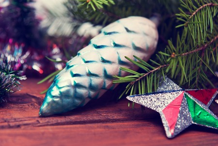 Branch of green fir tree with christmas toys on wooden background. Vintage toningの写真素材