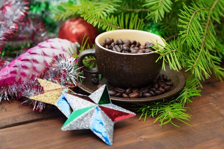 Branch of green fir tree with christmas toys and cup of coffee on wooden backgroundの写真素材