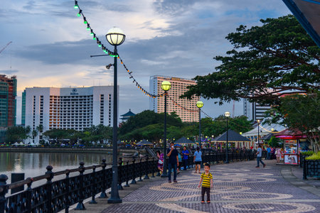 Kuching, Malaysia - Dec 29, 2015: Kuching city waterfront at sunset. People walk on the street. Sarawak. Borneo.のeditorial素材
