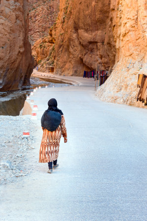 Tinghir, Morocco - Jan 05, 2017: Moroccan woman in traditional dressin goes to Todgha Gorge is canyon in Atlas Mountains, near Tinghir cityのeditorial素材