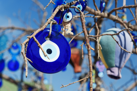 Nazars, Turkish Evil eye charms on the branches of tree on blue sky background in Cappadocia. Nevsehir Province. Turkeyの写真素材