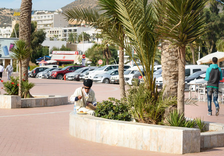 Agadir. Morocco - December 23, 2016: Moroccan man eating food on beach promenade in Agadir cityのeditorial素材