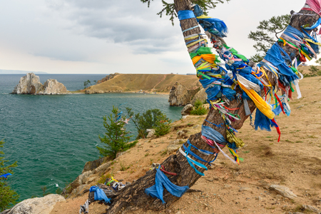 View of Shaman Rock and ritual tree with colorful ribbons Hadak in the overcast. Lake Baikal. Olkhon Island. Russiaの写真素材