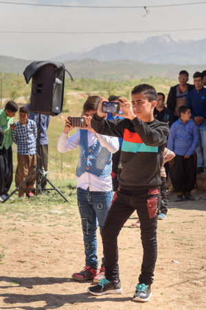 Lorestan Province, Iran - April 1, 2018: Iranian Children taking pictures with smartphone on wedding ceremony in the villageのeditorial素材