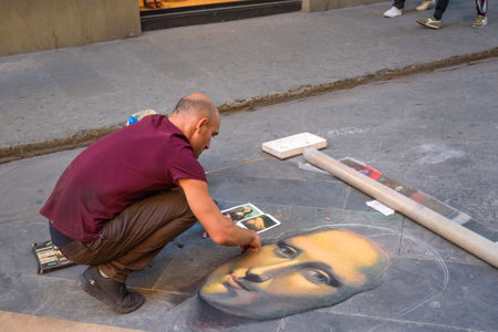 Florence, Italy - September 27, 2018: Painter drawing picture with chalk on asphalt in the streetのeditorial素材