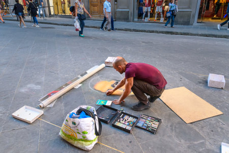 Florence, Italy - September 27, 2018: Painter drawing picture with chalk on asphalt in the streetのeditorial素材