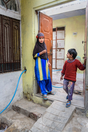 Amber village, India - January 30, 2019: Local Indian girl and boy standing at the door of house in Amer. Rajasthanのeditorial素材