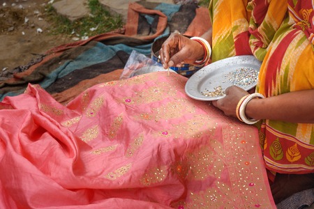 Indian woman decorates saree by sequins and beads, embroidering traditional sari in Amer village. Rajasthan. Indiaの写真素材